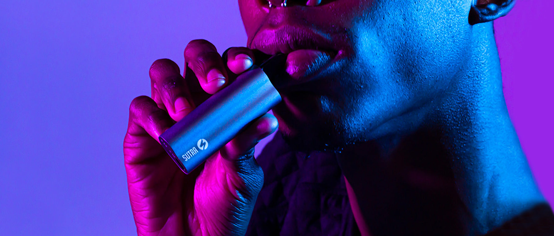 Man holding Sutra Auto Vaporizer in colorful studio background
