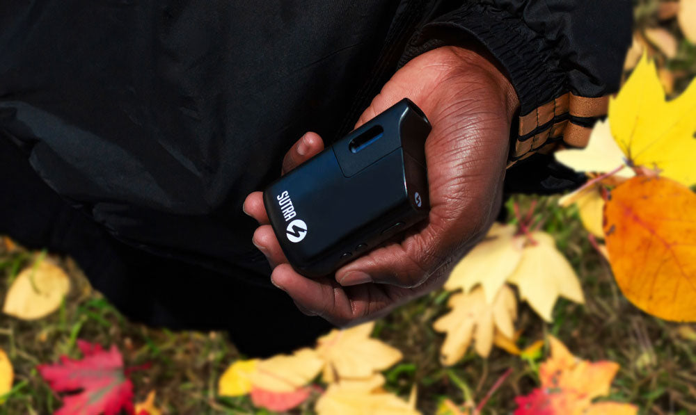 Man holding Sutra Mini above fall leaves