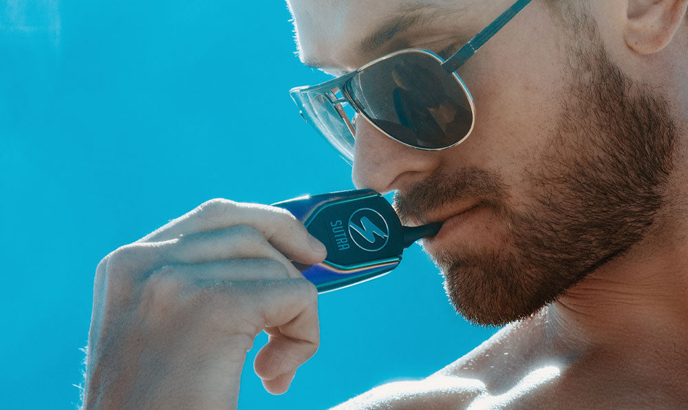 Man in sunglasses holding Sutra Squeeze under blue sky