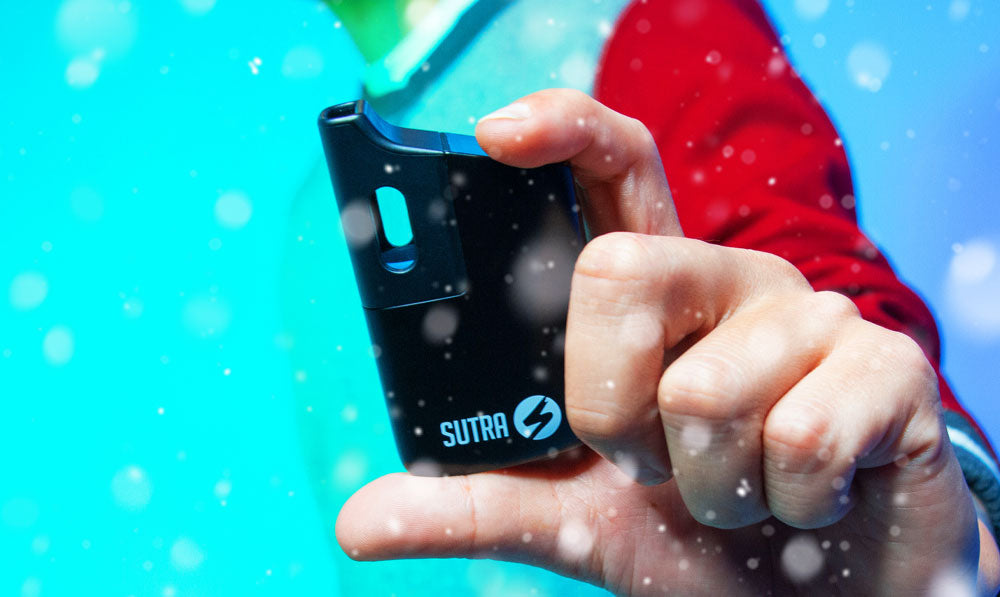 Man holding Sutra Mini in front of blue studio background with snow falling