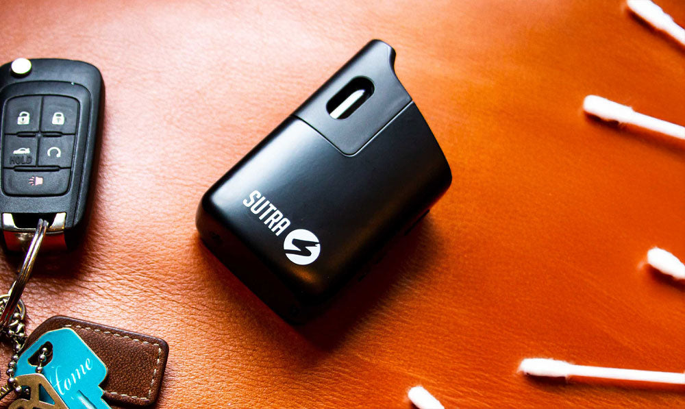 Sutra Mini resting on leather surface with house keys and q-tips nearby
