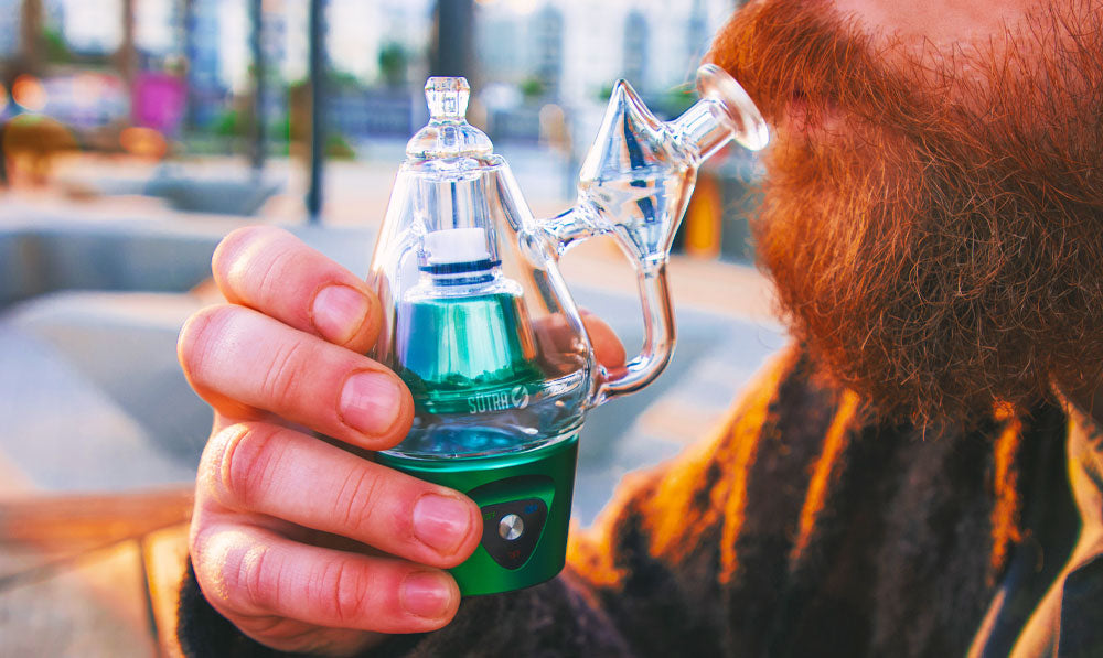 Bearded person holding a Sutra DBR Pro electronic rig with its glass attachment