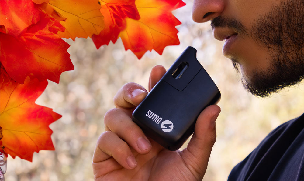 Man holding Sutra Mini with Fall leaves nearby