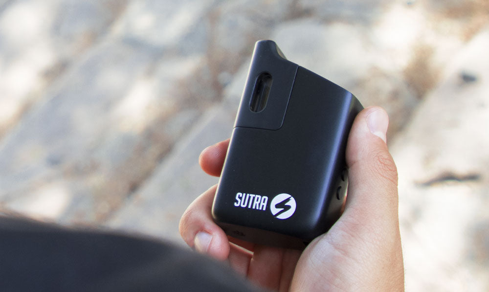 Man holding Sutra Mini on a park trail