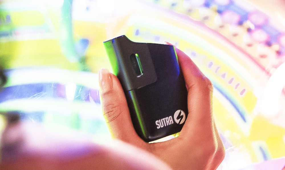 Woman holding Sutra Mini above arcade game