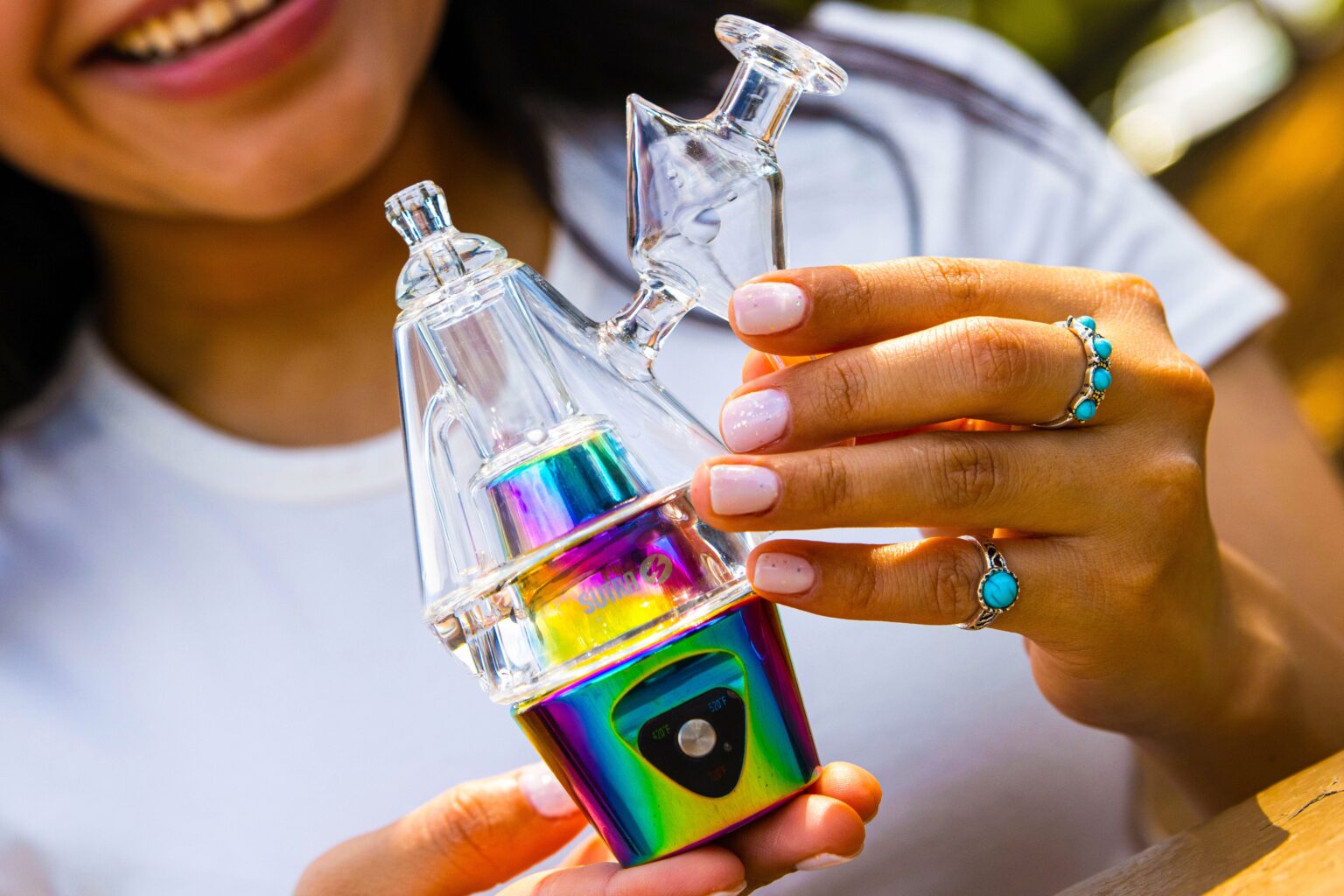 Sutra DBR Pro electronic rig in rainbow finish with its clear glass bubbler attachment, held in both hands